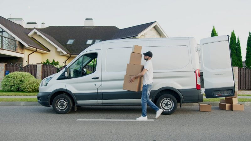 man carrying boxes beside a van