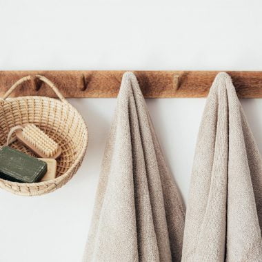 wooden hanger with towels and basket with bathroom products