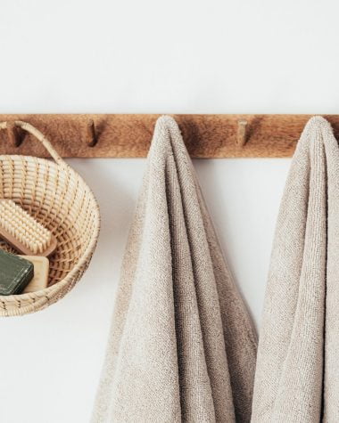 wooden hanger with towels and basket with bathroom products