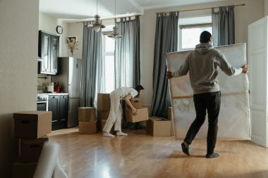 man in gray hoodie standing near white window curtain