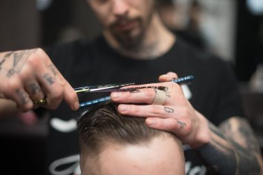 man cutting the hair on the person sitting on the chair